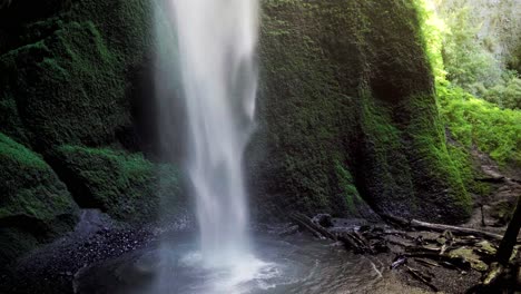 handheld of hidden mili mili misty waterfall streaming into natural pond surrounded by dense green vegetation, coñaripe, chile