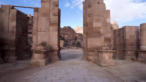 walking through the ruins of old and ancient stone gates with pillars on each side in ancient city of petra