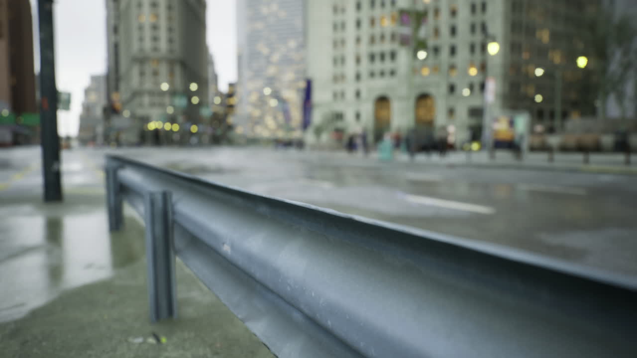 Urban landscape showcasing a raindrop soaked street and a metal barrier