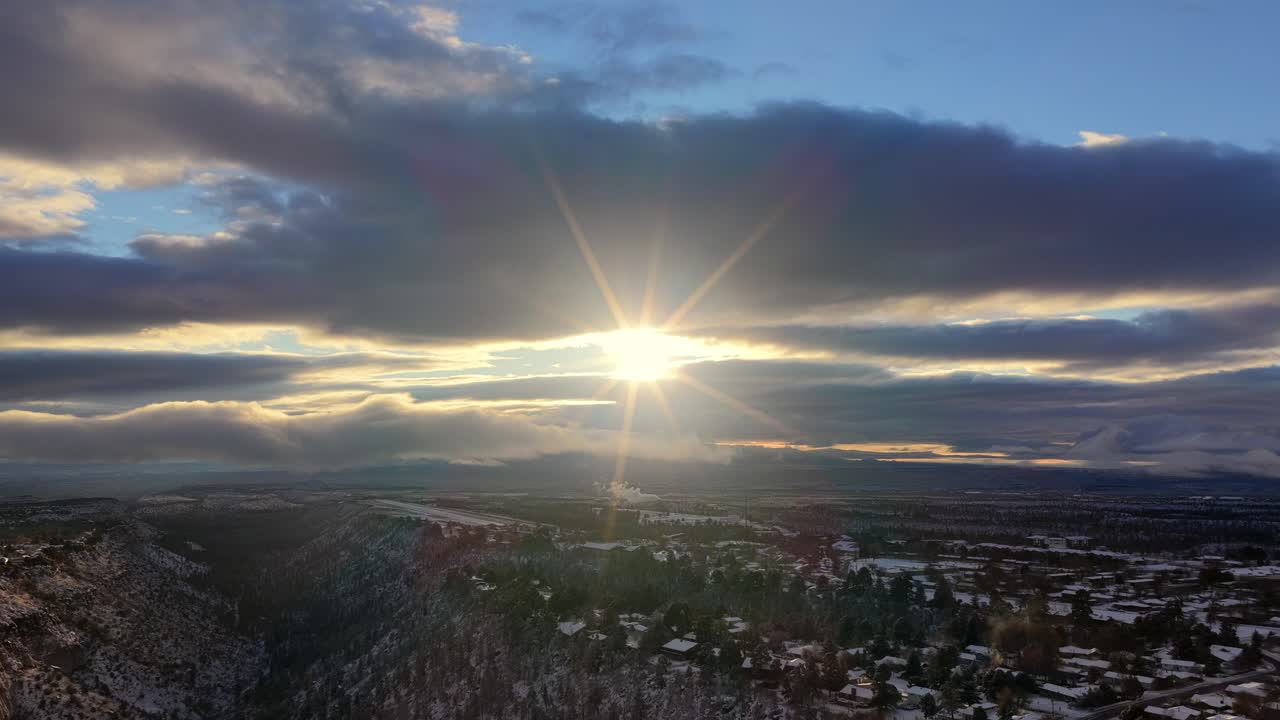 Expansive aerial view of a deep canyon and gorge system at sunrise. The forested slopes are dusted with snow, creating a beautiful winter scene in the high mountain terrain of the Southwest