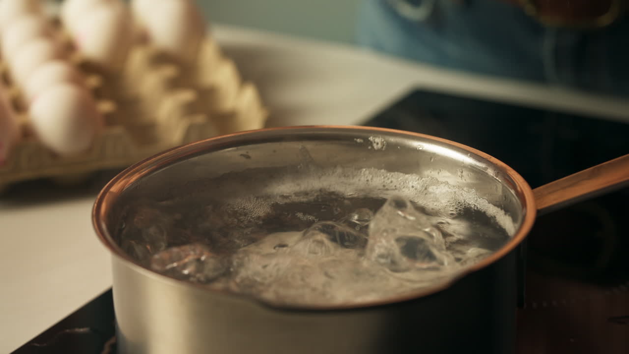 Boiling egg dropped into pot during Easter food preparation