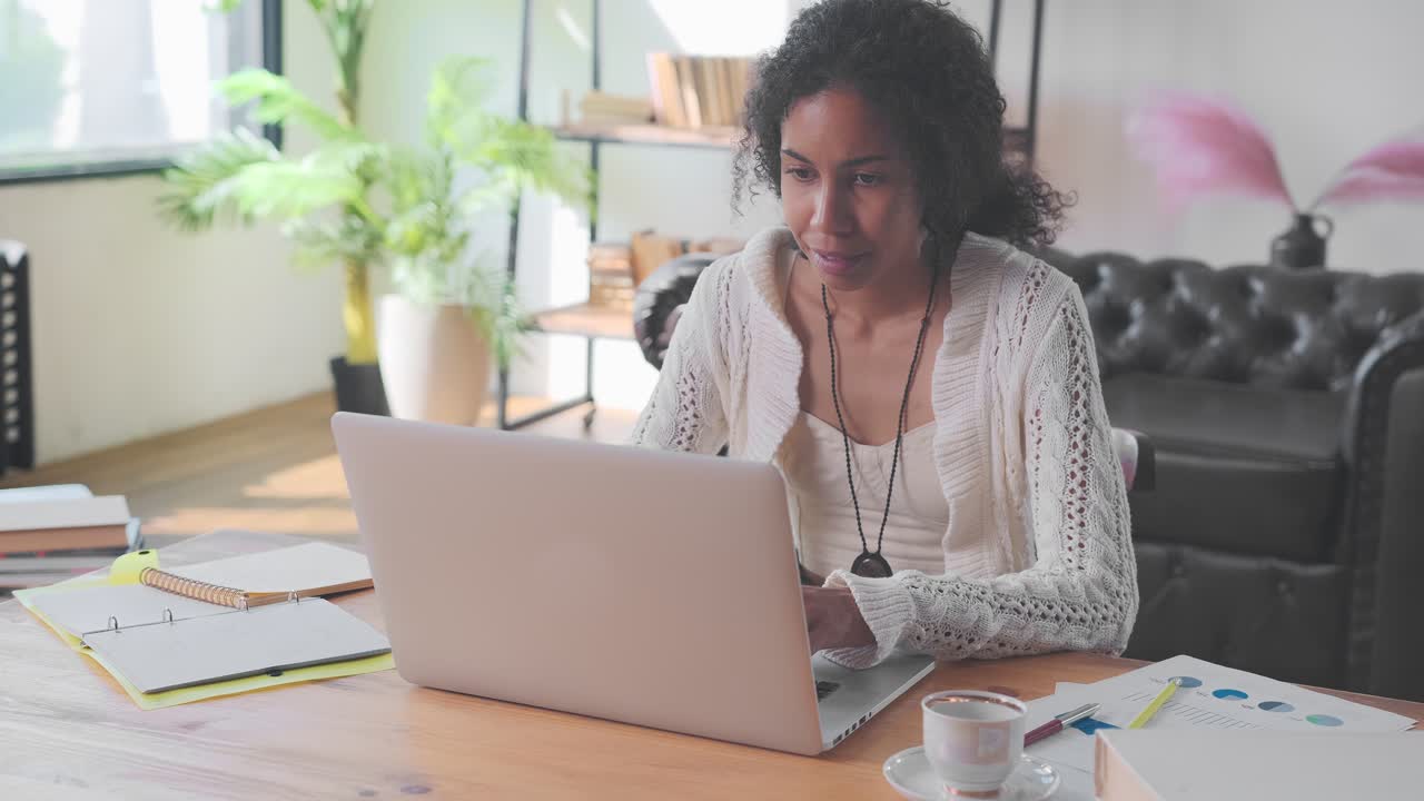 Young african american woman accountant uses laptop sits at office table