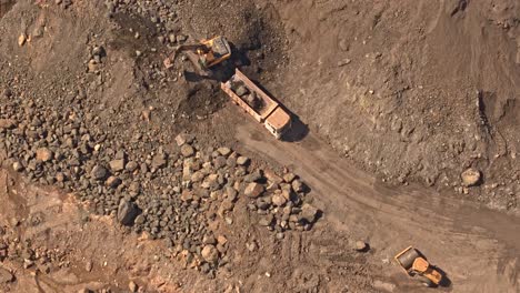 A-yellow-digger-moving-dirt-and-earth-into-the-back-of-a-truck-located-at-a-gold-and-silver-mine-in-Mainit,-Philippines