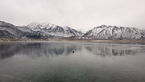 extreme wide shot of a lonely person digging ice for fishing on frozen crowley lake