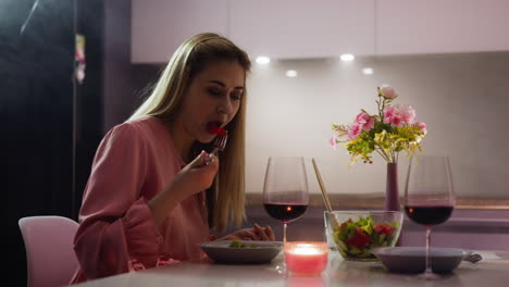 woman eats salad sitting at elegant served table in kitchen