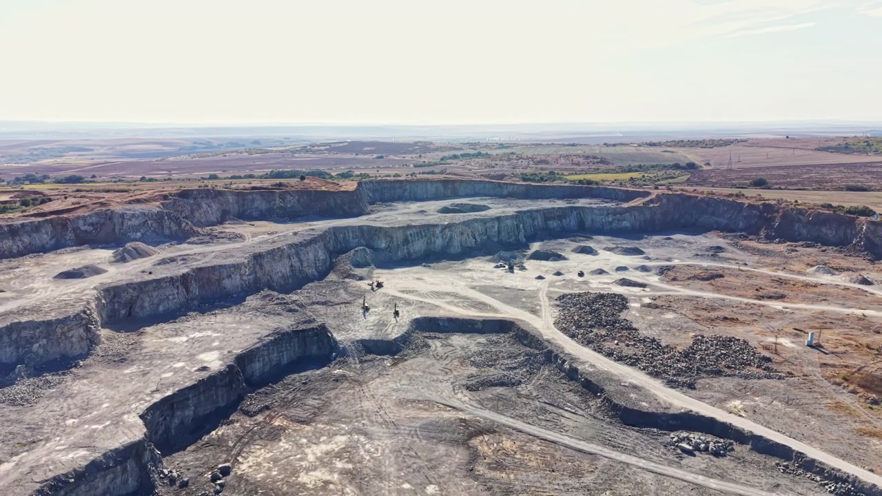 Granite quarry operation in a rural area during daytime with machinery and workers present