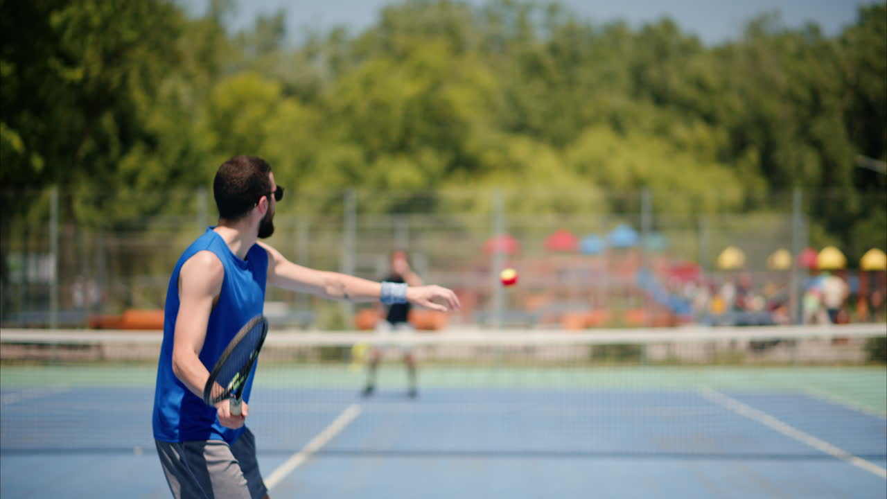 Two men playing tennis on a blue and green court on a sunny day