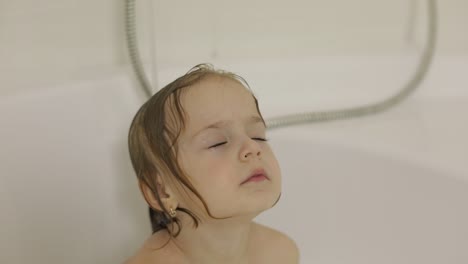attractive three years old girl takes a bath. cleaning and washing hair