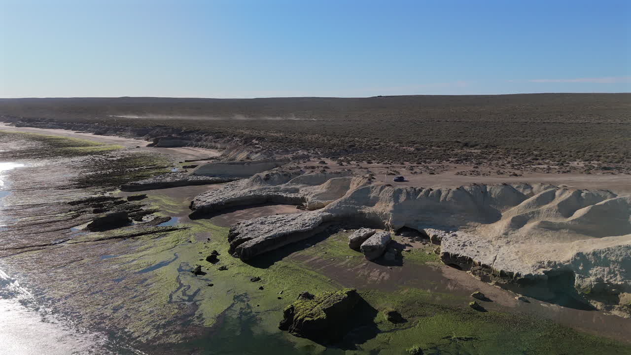 Aerial descend to Mirador Punta Ameghino in Puerto Madryn, showcasing its dramatic coastline and cliffs, strong textured with algal bloom