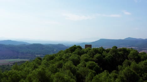 Drone-flies-past-a-Historic-European-Watchtower-Perched-on-a-Mountain-top-revealing-an-Epic-Rural-Spanish-Landscape,-Aerial