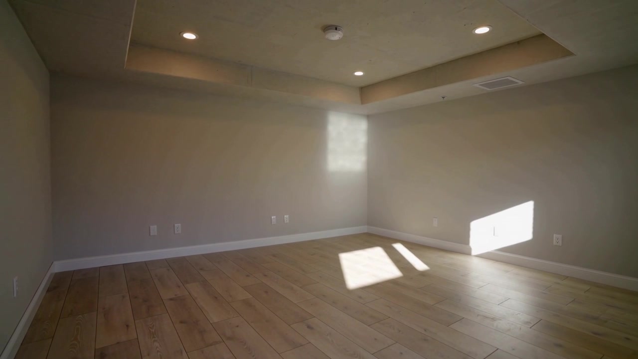 Panning camera revealing finished room at home, showing tray ceiling, downlights, sunlight patch