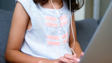 chica con auriculares usando una computadora portátil en la sala de estar