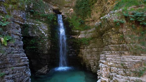 Paisaje-De-Cascada-Del-Paraíso-Con-Agua-Limpia-Que-Hace-Espuma-En-Un-Estanque-Esmeralda-Rodeado-De-Rocas-En-Albania