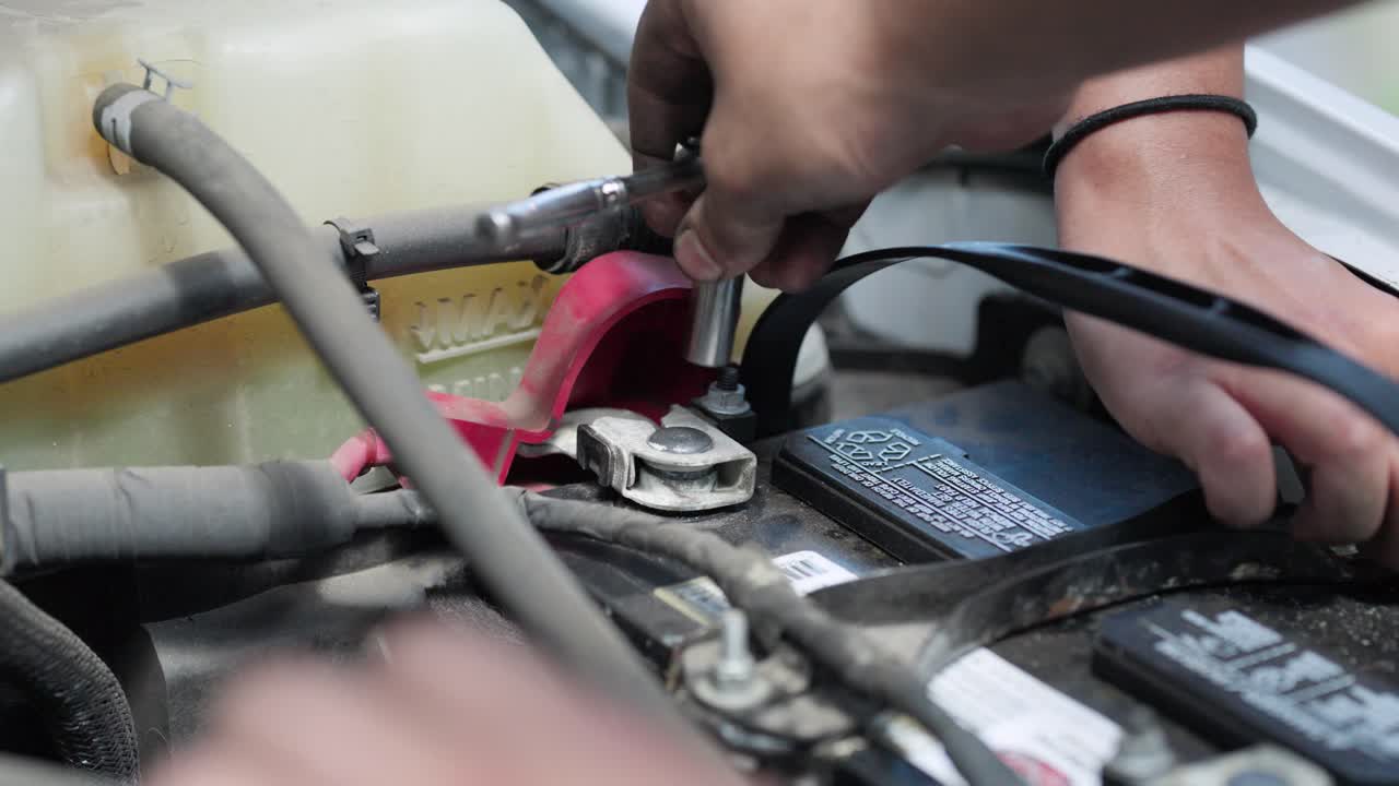 車のバッテリーを元の位置にラチェットで固定する整備士