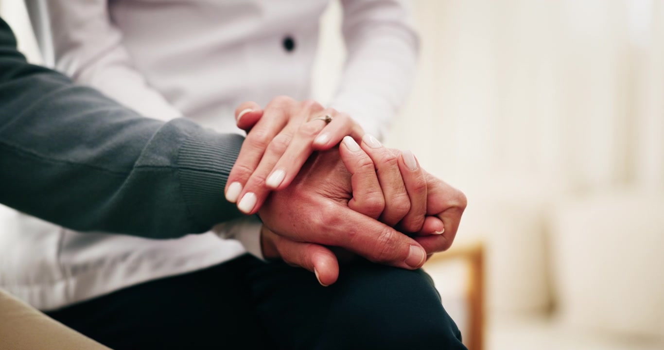Primo piano di una donna che conforta una persona anziana tenendole le mani