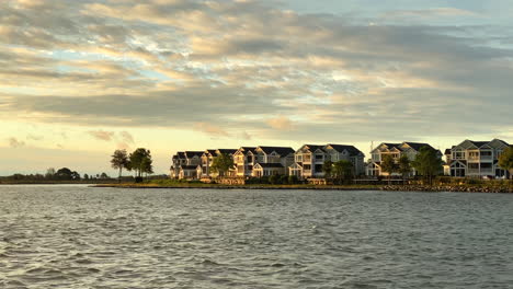 a row of beach houses along the shoreline nearby the ocean in the sunrise light