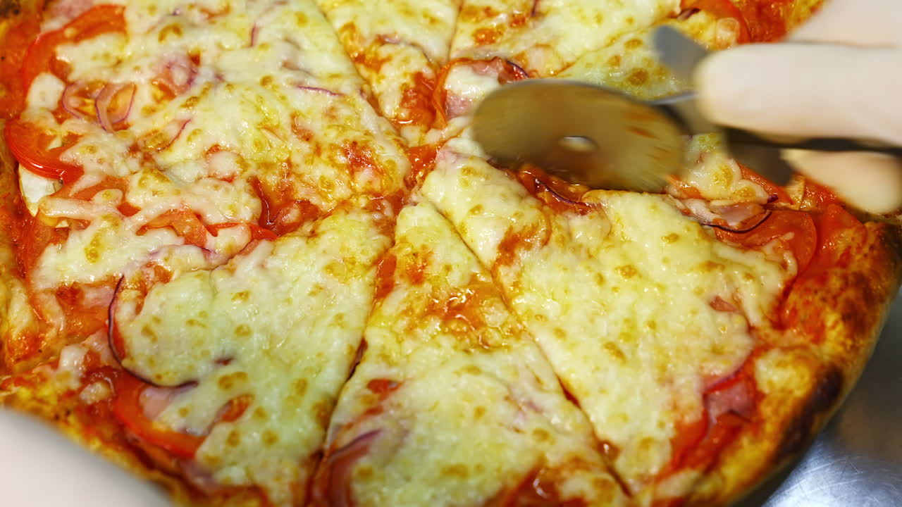 Yummy fresh pizza in a restaurant. Just now cooked pizza from oven cutted in pieces with pizza knife. Much cheese on the top.