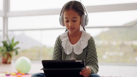 niña, auriculares y tableta en el hogar