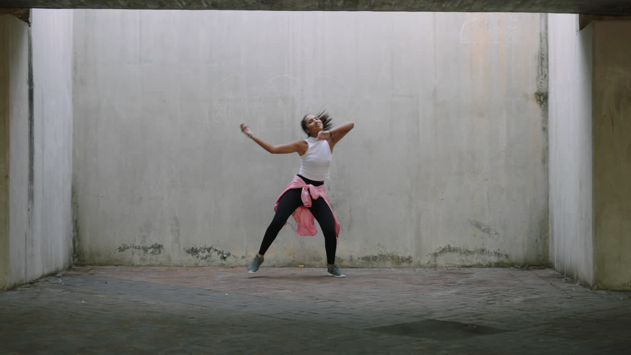 mujer bailarina joven bailarina de calle de raza mixta realizando movimientos de hip hop de estilo libre disfrutando de la expresión de danza moderna practicando en un almacén grungy