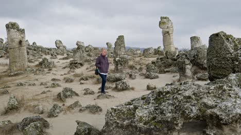 lonely woman wanders among ancient natural rock formations in silence