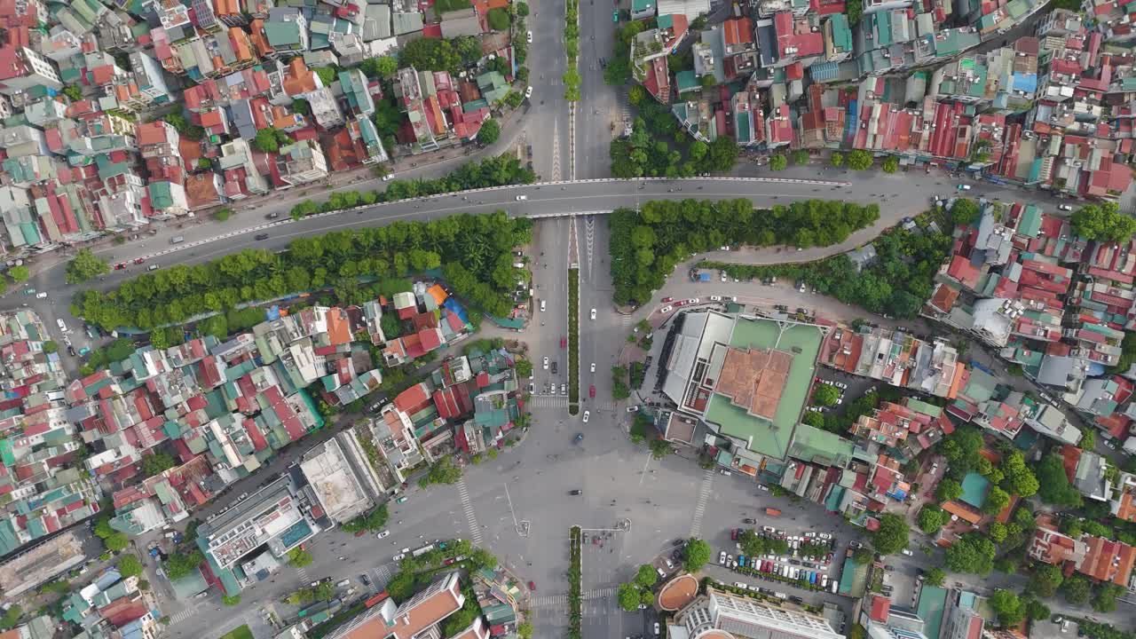 A top-down aerial drone view of a bustling urban intersection in Hanoi, Vietnam. The dense network of streets and buildings with vehicles moving through the traffic. UHD
