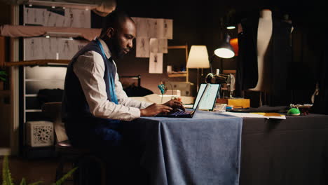 Male-couturier-using-laptop-in-atelier