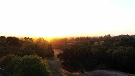 Pan-right-over-a-smokey-fog-covered-forest-right-at-sunrise,-daybreak,-golden-hour,-stunning-colors