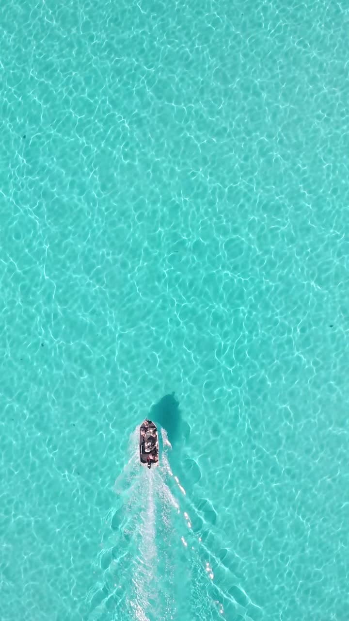 A vertical shot of a boat in the turquoise water