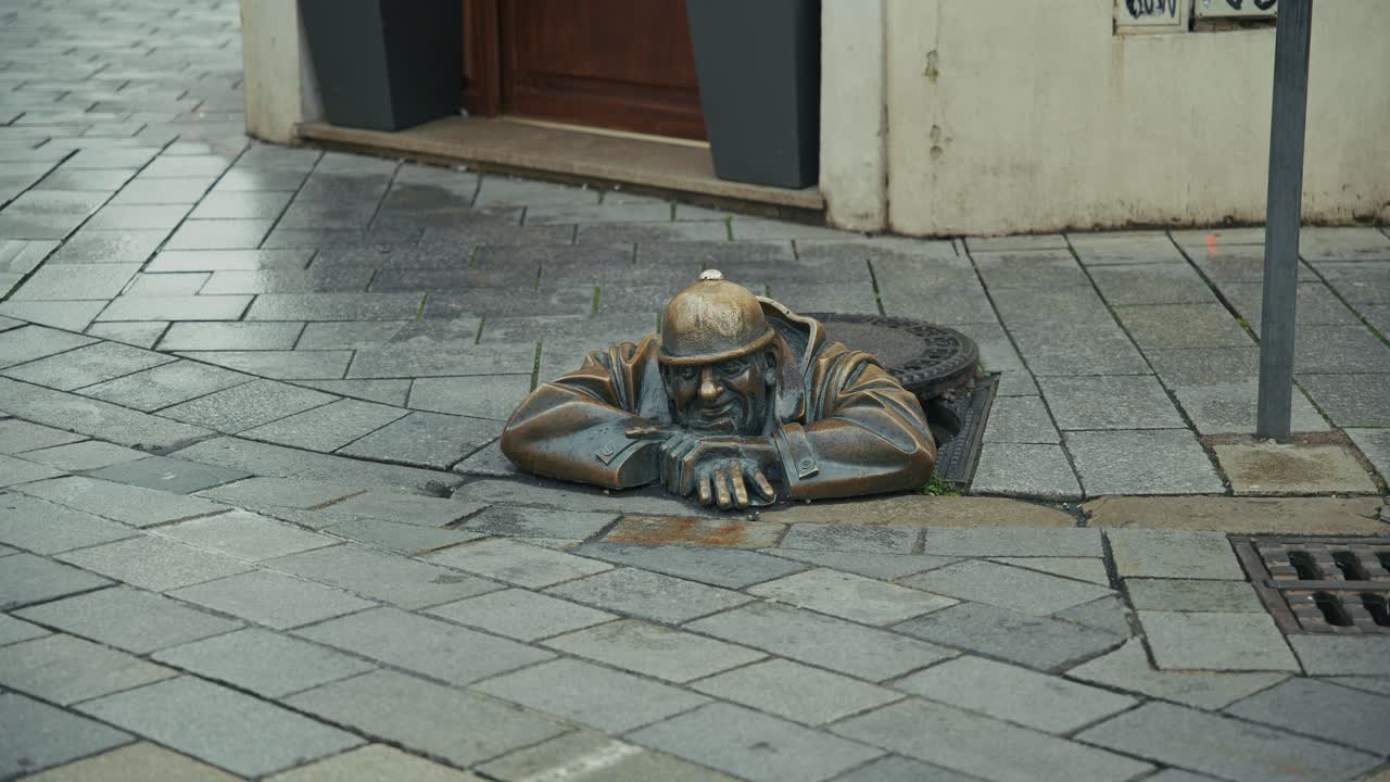 famous Čumil bronze statue of a sewer worker emerging from a manhole in Bratislava