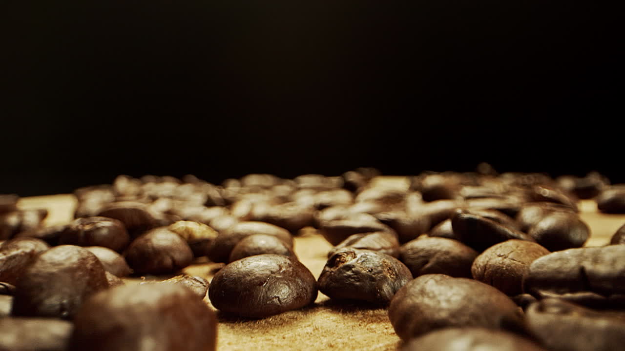 通过新鲜的咖啡豆在木质表面上进行紧密的摄像头运动