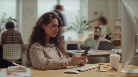 time lapse of young woman using smartphone at desk in busy office