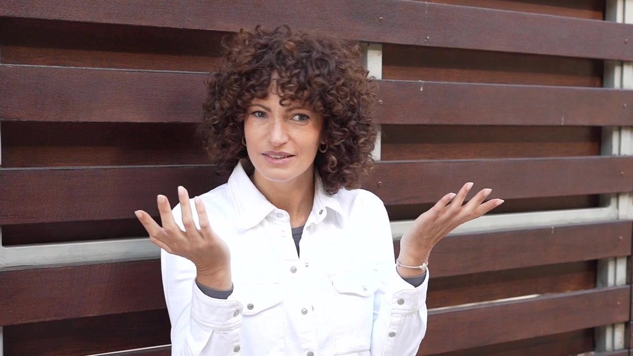 A beautiful portrait of a confident woman featuring curly hair set against a wooden background