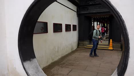 European-tourist-man-crossing-a-hole-in-Yuyuan-Garden,-Shanghai