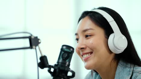 content creator woman host streaming his a podcast on laptop with headphones and condenser microphone interview guest conversation at home broadcast studio. female blogger recording voice over radio.