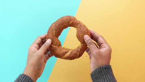 hands holding a sesame bagel (simit)