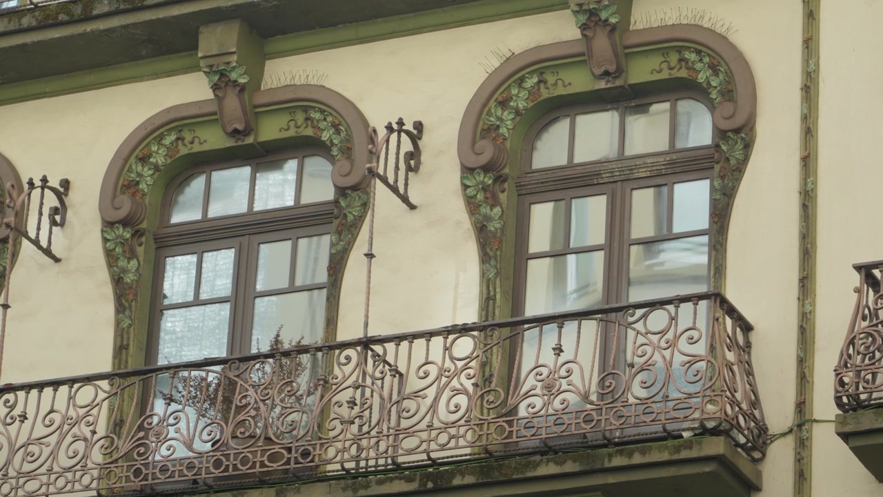 Ferforje balkonları ve kavisli pencereleriyle modernisme tarzı bir binanın süslü cephesinden detay