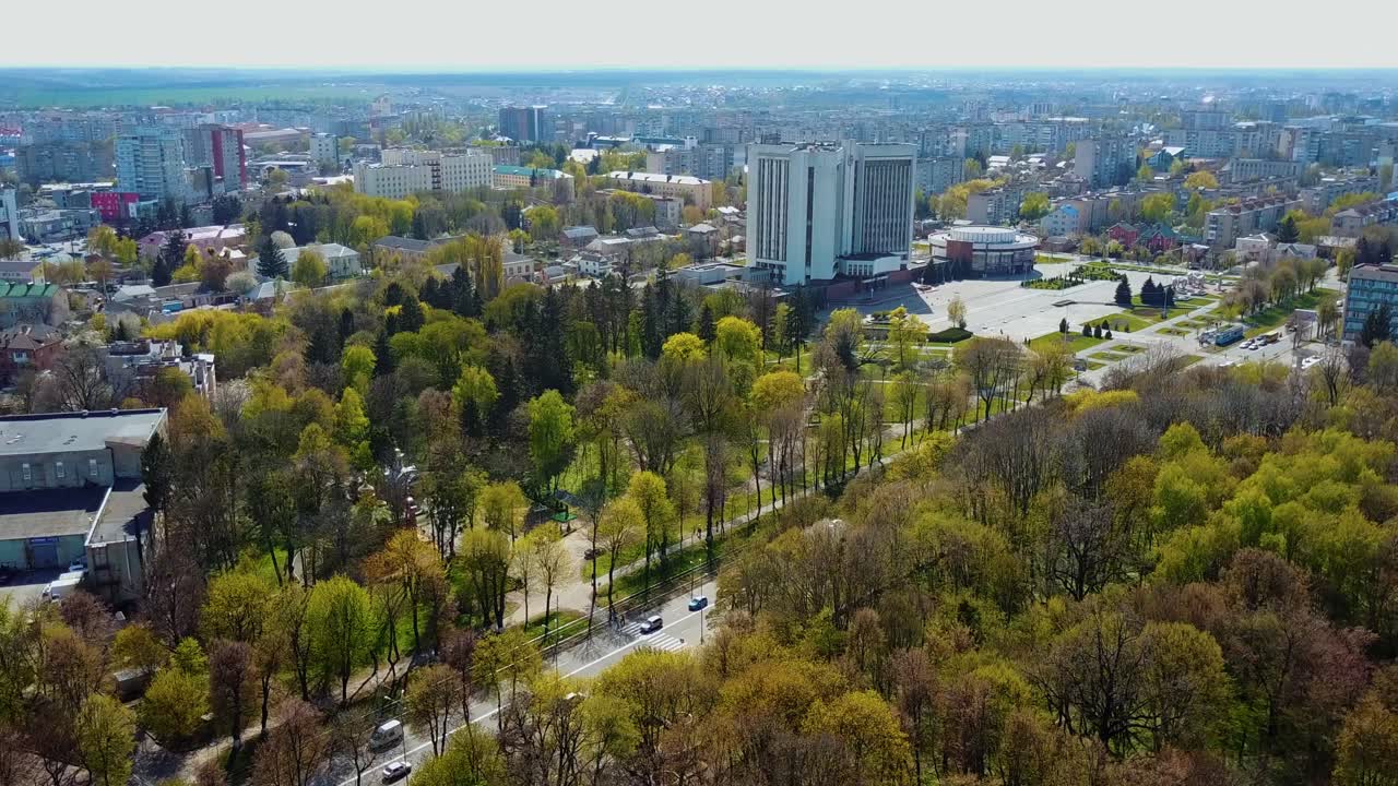 High altitude aerial view over the city at spring. Flight over the beautiful buildings and green trees in the city center. Aerial view.
