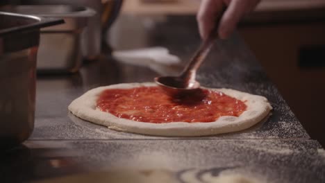 chef preparing pizza base with tomato sauce