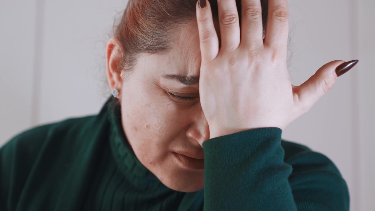 Donna ansiosa concentrata sul suo dispositivo. La donna mostra stress mentre usa il suo smartphone vicino alla finestra. Appare tesa e preoccupata mentre interagisce con il suo dispositivo mobile vicino alla finestra.