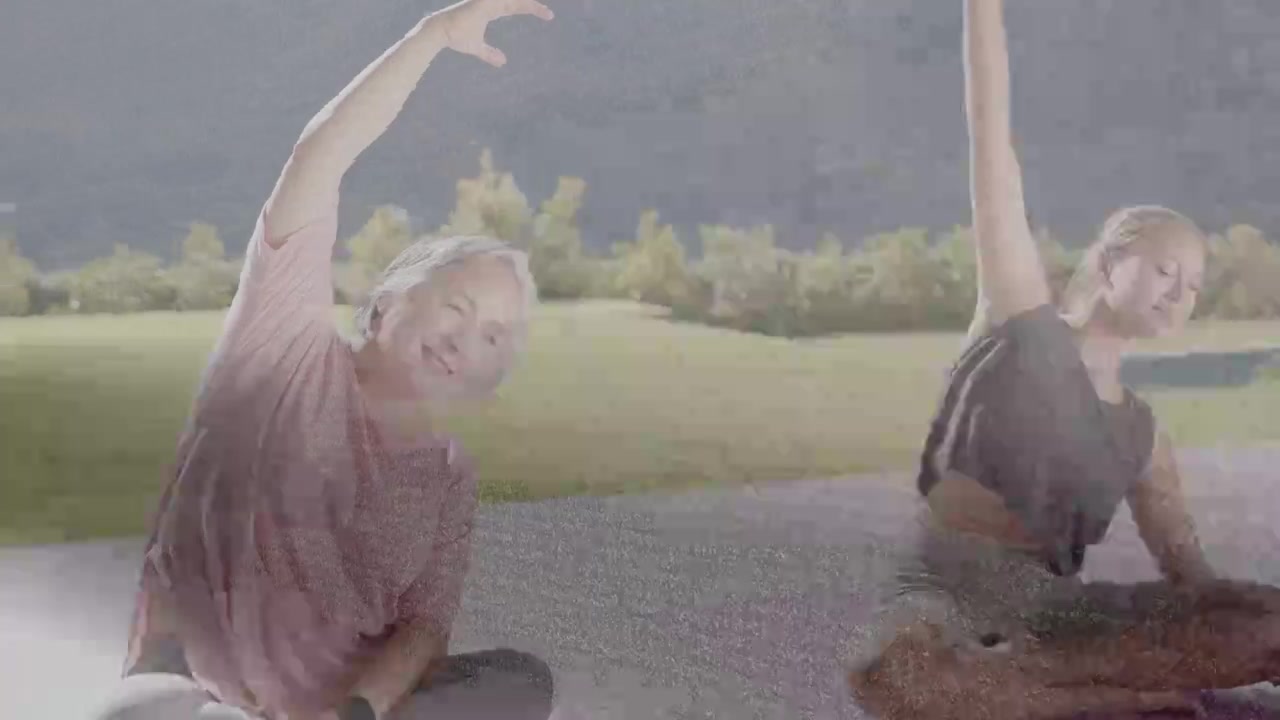 Dışarıda fitness yapan iki kadın; olgun kadın kolunu kaldırıyor, genç onu taklit ediyor, minderlerde bileklik takıyorlar.