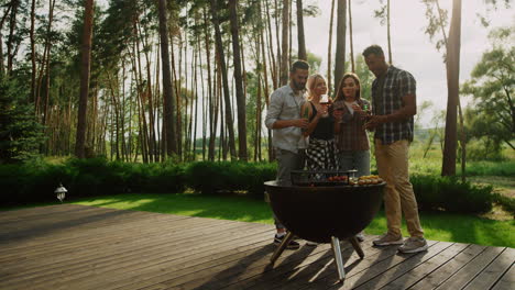 multiracial friends having rest on grill party outside. people cooking bbq food