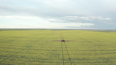 Maquinaria-Agrícola-Aplicando-Insecticida-En-Hermosos-Campos-De-Canola-Amarillo-Vibrante-En-Canadá