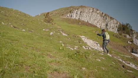 Hiker-walkinh-up-a-hill-on-a-rocky-path,-clear-sky