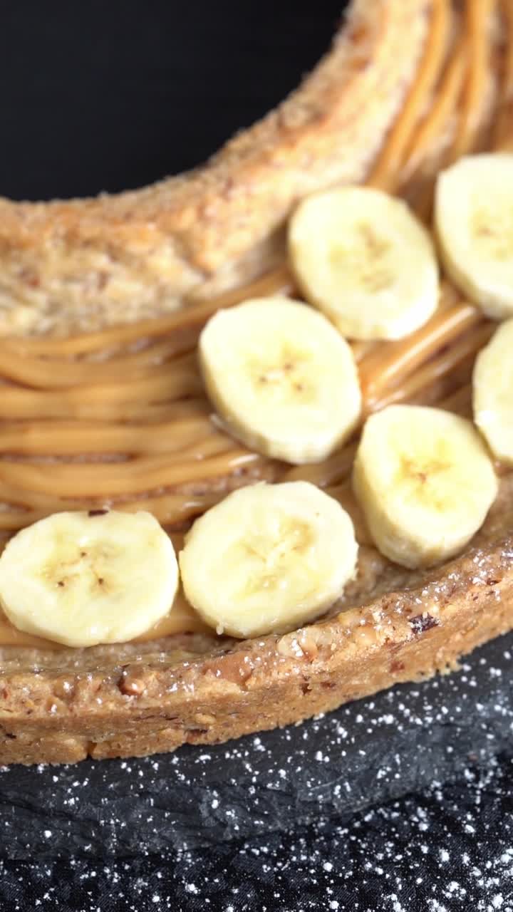 A chief adds banana slices to a cake, close up shot, insert shot