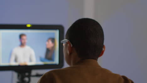 vista trasera de una directora de cine observando el rendimiento de un actor masculino en el monitor filmando o grabando video en el estudio 1