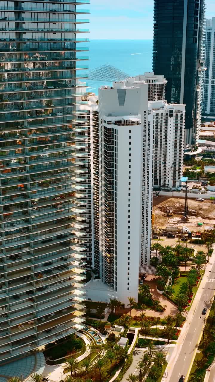 Discendendo sopra l'autostrada trafficata nella soleggiata Miami Beach, Florida, USA. Lussuosi grattacieli si allineano sulla costa dell'Oceano Atlantico. Video verticale