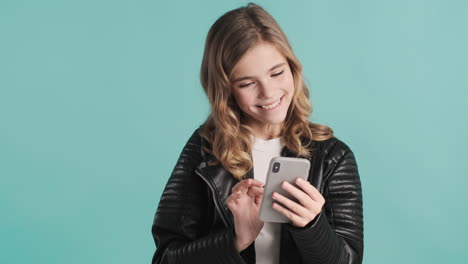 teenage caucasian girl in leather jacket using her smartphone.