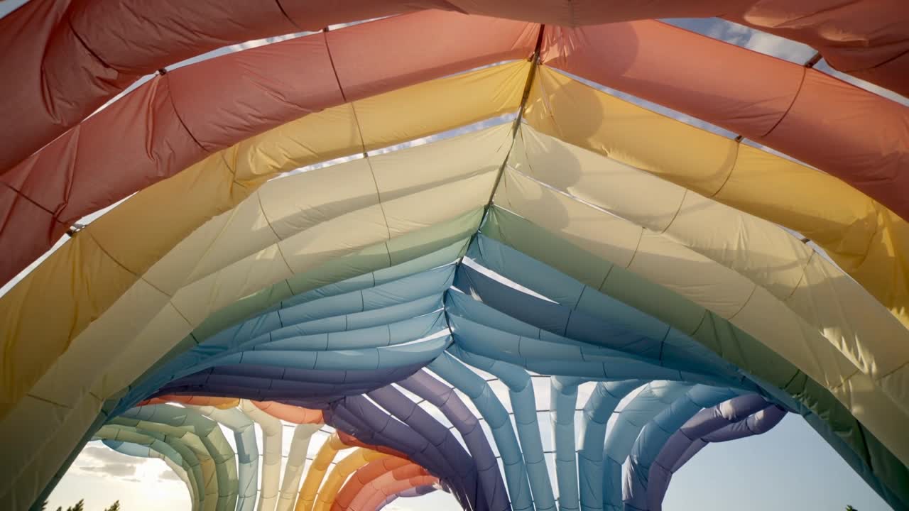 Pulsing inflatable canopy arches swaying in light breeze under park sky, revealing sewn ribs