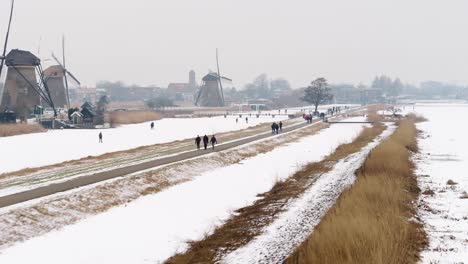 네덜란드 남부 네덜란드 지방의 kinderdijk 마을에 있는 상징적인 18세기 풍차 주변의 보도를 따라가는 겨울 풍경의 계속되는 항공 영상