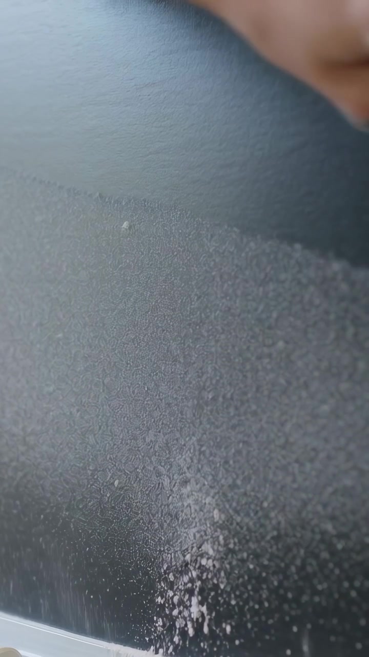 Vertical video: Spotting specks, wiping hand rubbing cloth on textured dark wall in room, cleaning